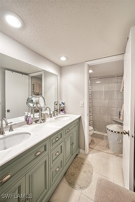 full bathroom with tile patterned flooring, a textured ceiling, toilet, and a sink