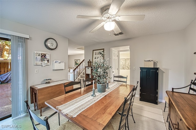 dining room featuring visible vents, a textured ceiling, baseboards, ceiling fan, and stairs