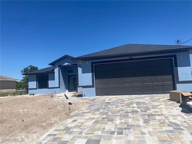 view of front facade featuring decorative driveway, a garage, and stucco siding