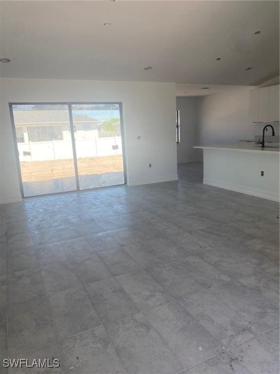 unfurnished living room with baseboards and a sink