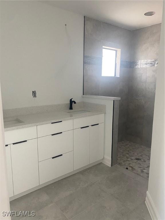 bathroom with double vanity, tile patterned floors, a walk in shower, and a sink