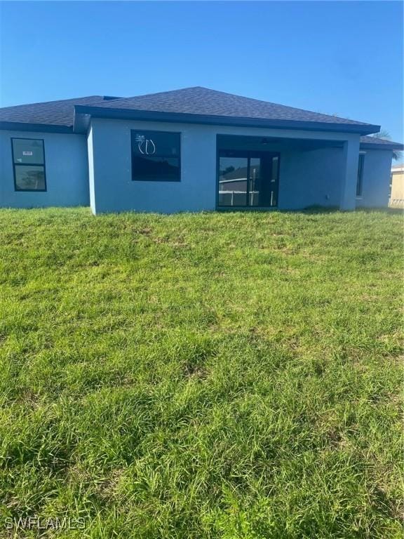 4108 35th St SW, Lehigh Acres, FL 33976 - rear view of house featuring stucco siding, a yard, and a shingled roof