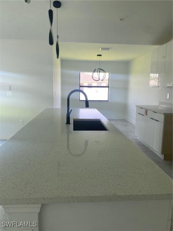 4108 35th St SW, Lehigh Acres, FL 33976 - kitchen featuring a sink, light stone countertops, white cabinets, hanging light fixtures, and modern cabinets