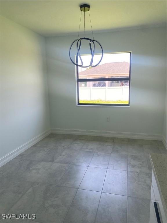 4108 35th St SW, Lehigh Acres, FL 33976 - tiled spare room featuring baseboards and a chandelier