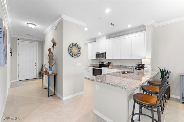 kitchen featuring a sink, appliances with stainless steel finishes, a kitchen bar, and crown molding