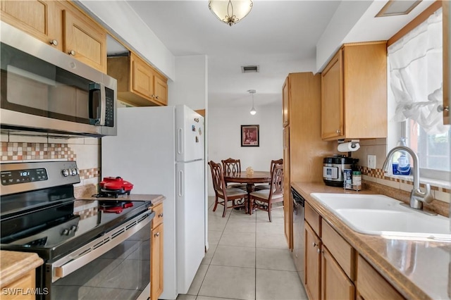 kitchen featuring visible vents, a sink, stainless steel appliances, light tile patterned flooring, and decorative backsplash