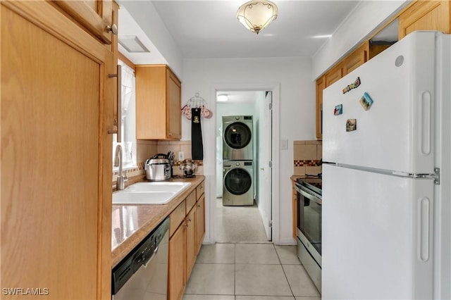 kitchen with decorative backsplash, appliances with stainless steel finishes, stacked washing maching and dryer, light tile patterned flooring, and a sink