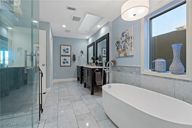 bathroom featuring visible vents, marble finish floor, vanity, and a freestanding tub