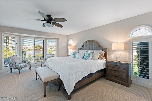 bedroom with a ceiling fan, light colored carpet, and baseboards