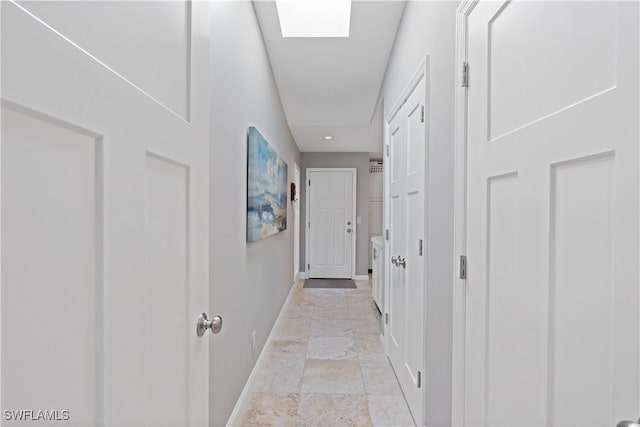 hall featuring stone finish flooring, baseboards, and a skylight