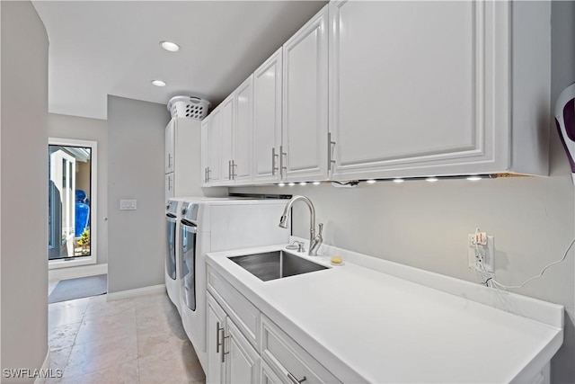 laundry room with baseboards, recessed lighting, cabinet space, a sink, and washer and clothes dryer