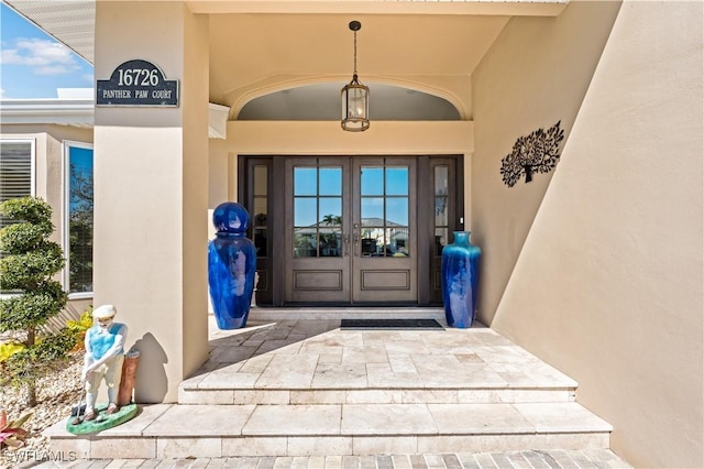 entrance to property featuring stucco siding and french doors