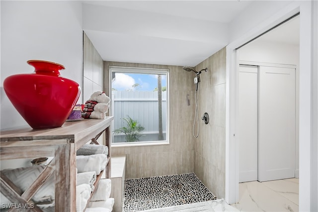 full bathroom with tiled shower and marble finish floor