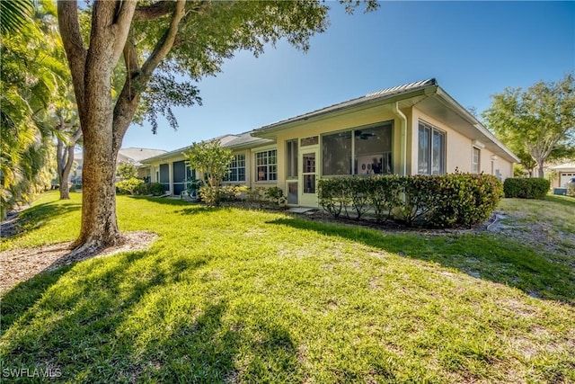 8664 Patty Berg Ct, Fort Myers, FL 33919 - rear view of property featuring stucco siding, a lawn, and a sunroom