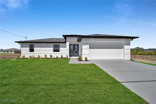 prairie-style home with concrete driveway, french doors, a garage, and a front lawn