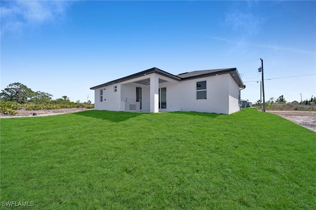 back of property with a lawn and stucco siding