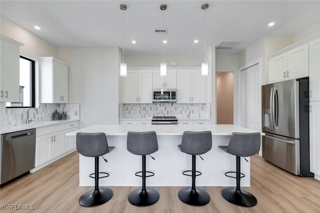 kitchen featuring light wood finished floors, light countertops, appliances with stainless steel finishes, white cabinets, and a sink