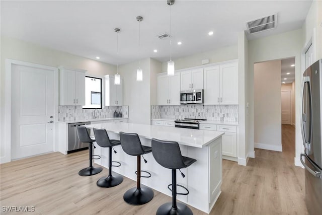 kitchen featuring stainless steel appliances, visible vents, a breakfast bar area, and light countertops