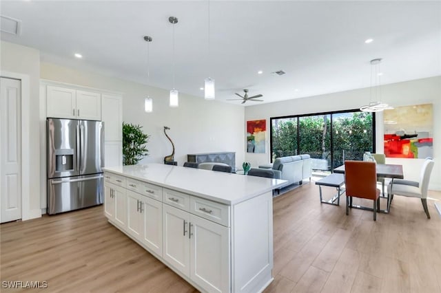 kitchen with light wood-style flooring, a kitchen island, white cabinetry, stainless steel fridge, and light countertops