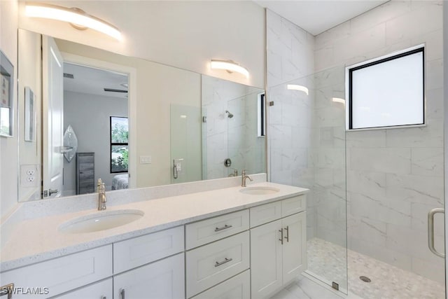 bathroom with a marble finish shower, ensuite bathroom, and a sink