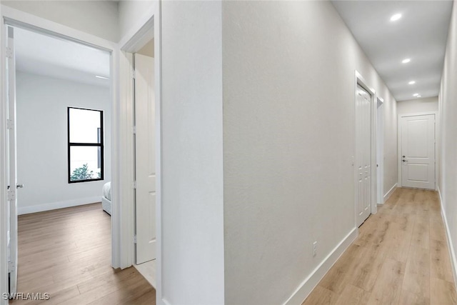 hall with recessed lighting, light wood-type flooring, and baseboards