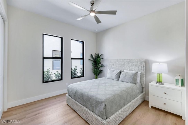 bedroom with light wood-style floors, baseboards, and ceiling fan