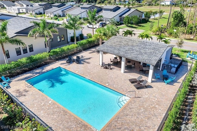 community pool with a patio area, a residential view, and fence