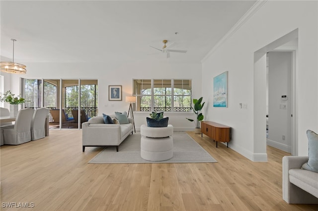 living area with light wood-style flooring, ceiling fan with notable chandelier, crown molding, and baseboards