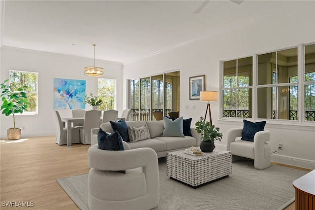 living room featuring light wood-style flooring, baseboards, ornamental molding, and a chandelier