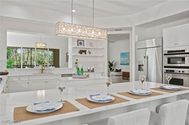 kitchen featuring a sink, stainless steel appliances, light stone counters, and white cabinetry