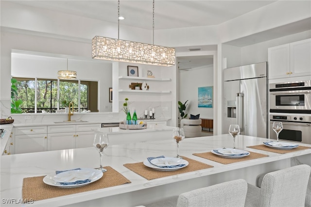 2882 Castillo Ct Unit 103, Naples, FL 34109 - kitchen featuring a sink, stainless steel appliances, light stone counters, and white cabinets