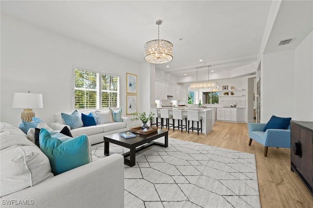 living area featuring light wood-type flooring, visible vents, a chandelier, and recessed lighting