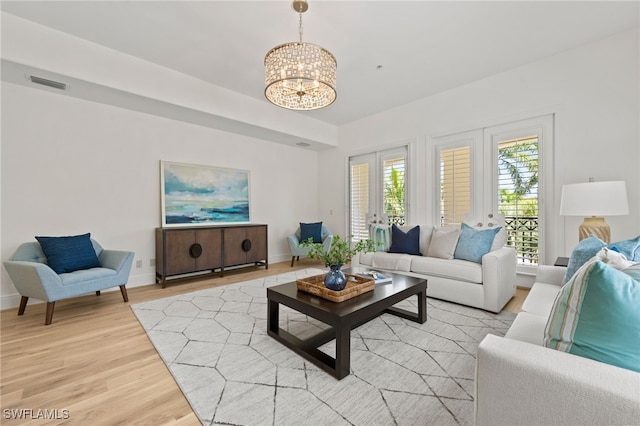 living area featuring a notable chandelier, visible vents, light wood-type flooring, and baseboards