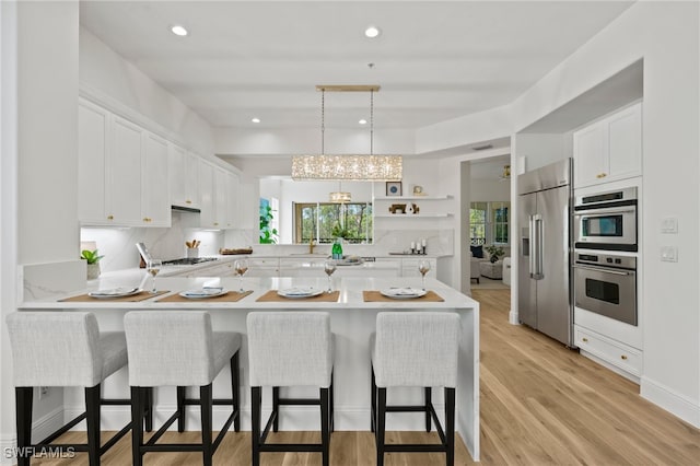 kitchen featuring a peninsula, white cabinets, a kitchen breakfast bar, and appliances with stainless steel finishes