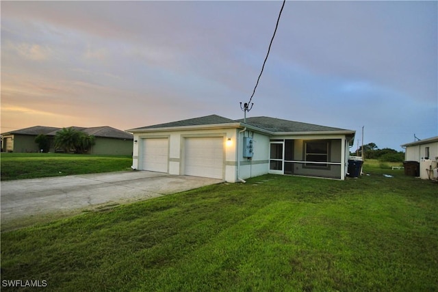 view of front of property with driveway, a yard, a sunroom, stucco siding, and a garage