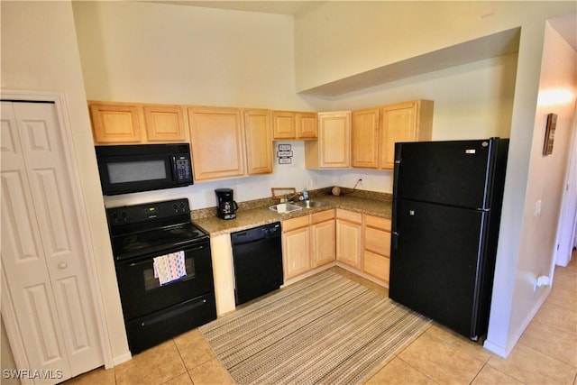 kitchen featuring light brown cabinets, light tile patterned floors, a high ceiling, black appliances, and a sink