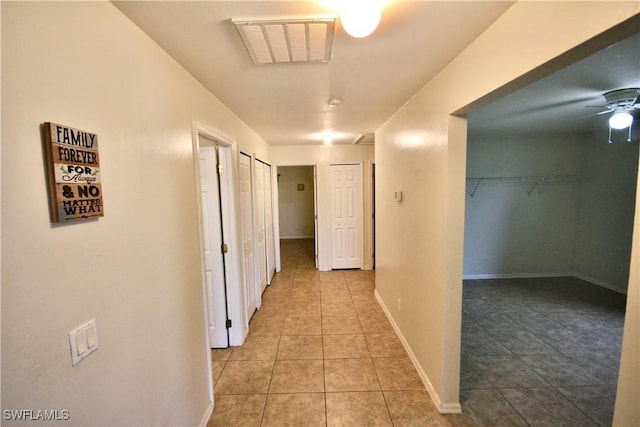 hallway with light tile patterned flooring, visible vents, and baseboards