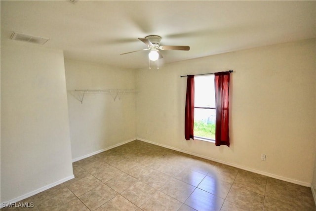 empty room featuring tile patterned floors, visible vents, baseboards, and ceiling fan