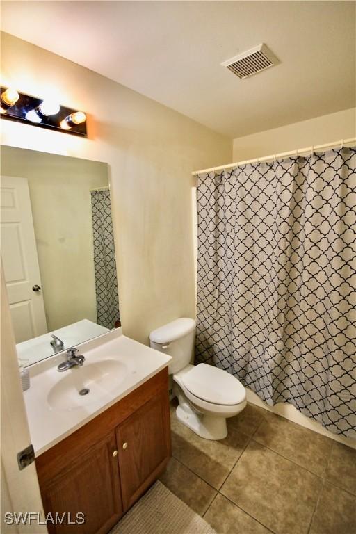 bathroom with vanity, visible vents, tile patterned flooring, curtained shower, and toilet