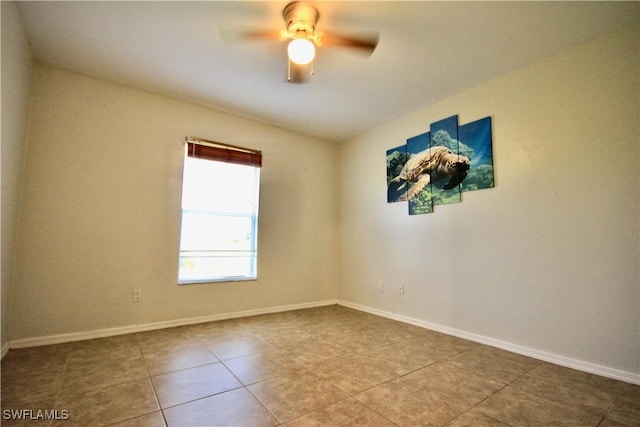 tiled spare room with baseboards and ceiling fan