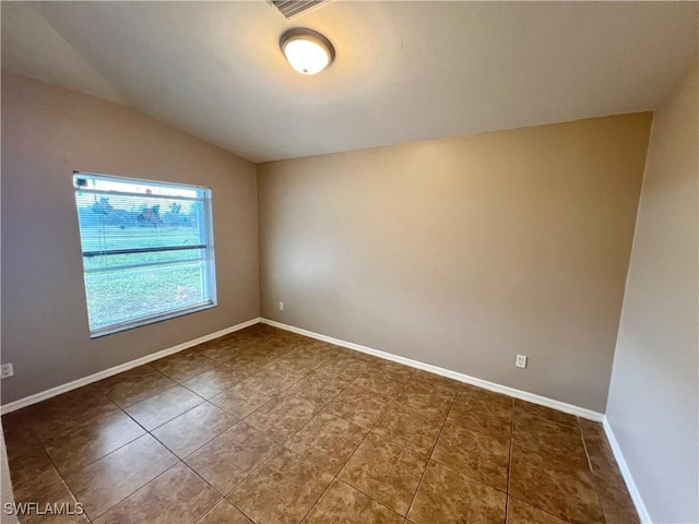 tiled empty room with baseboards and lofted ceiling