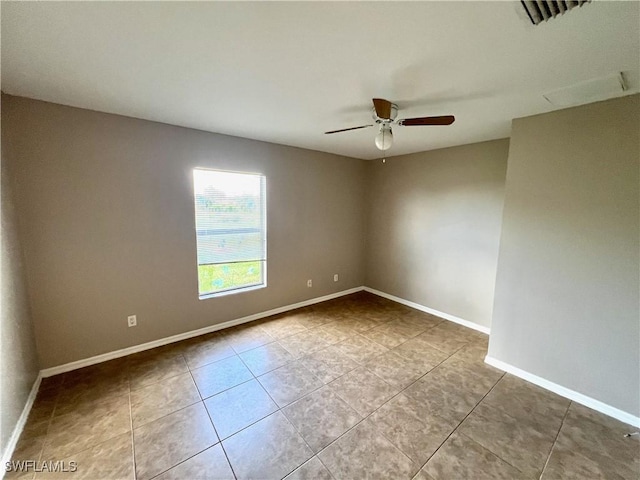 tiled spare room with visible vents, baseboards, and ceiling fan