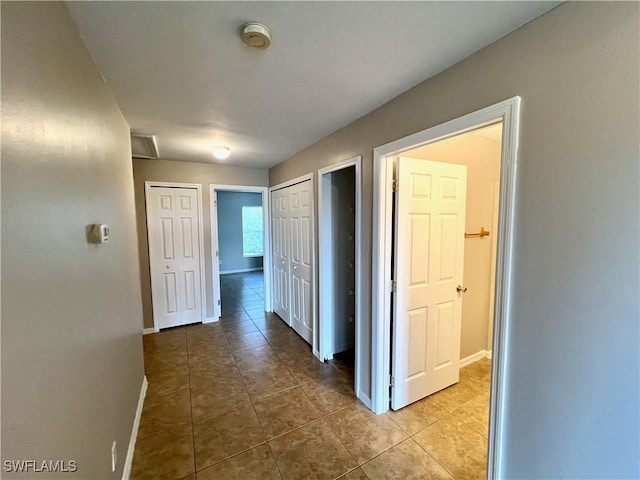 corridor featuring tile patterned flooring and baseboards