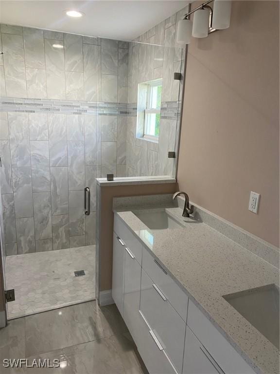full bathroom with recessed lighting, double vanity, a stall shower, and a sink