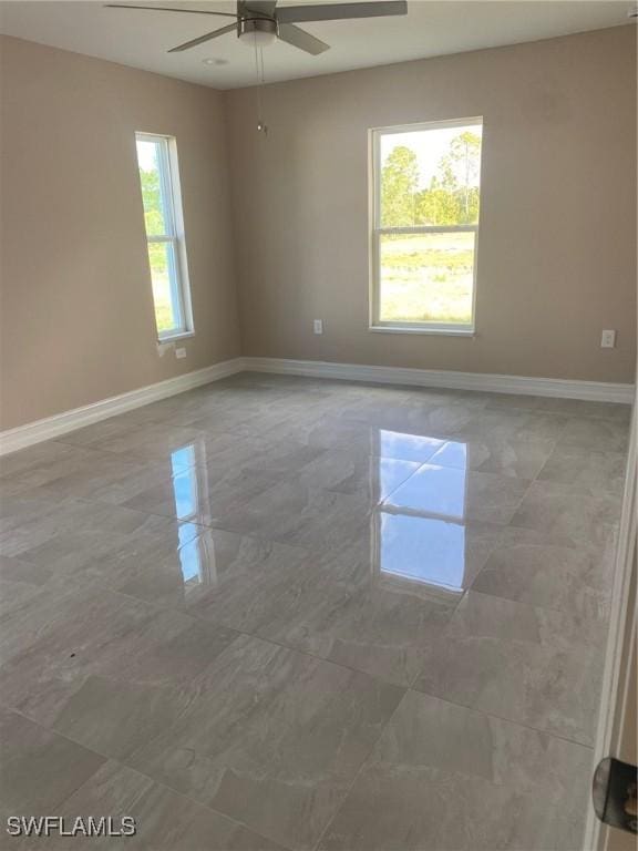 spare room featuring a ceiling fan and baseboards