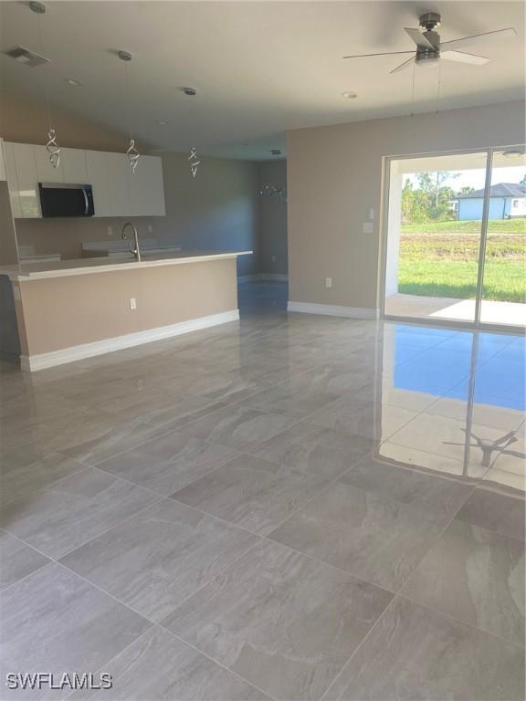 2910 28th St W, Lehigh Acres, FL 33971 - unfurnished living room with baseboards and ceiling fan