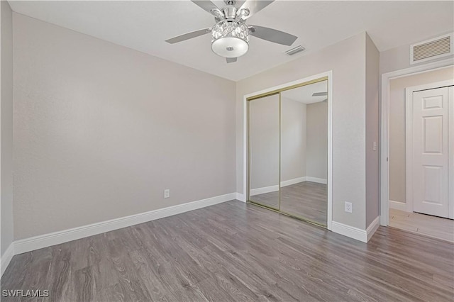 unfurnished bedroom with visible vents, baseboards, a closet, and wood finished floors