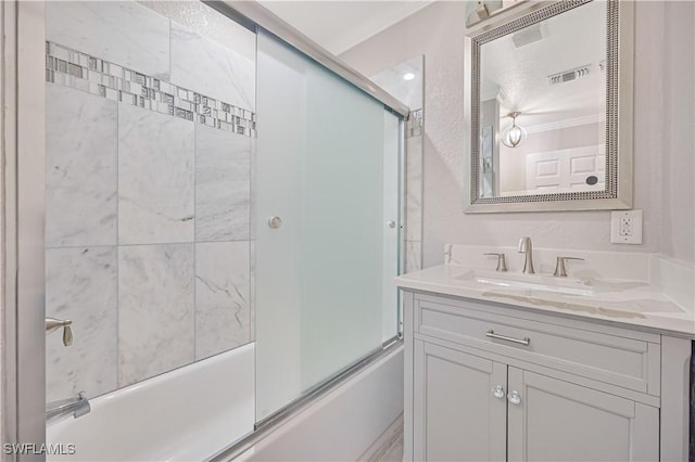 bathroom with vanity, crown molding, visible vents, and enclosed tub / shower combo