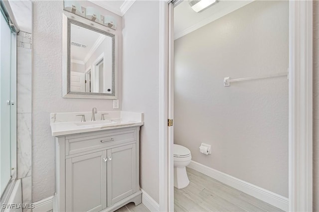 bathroom featuring vanity, wood finished floors, baseboards, crown molding, and toilet