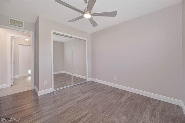 unfurnished bedroom with a ceiling fan, wood finished floors, visible vents, baseboards, and a closet